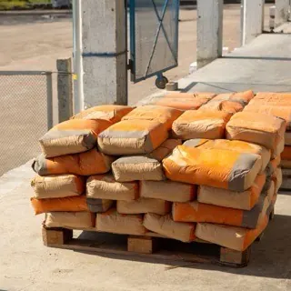 Bao xi măng giấy màu cam xếp chồng trên pallet gỗ