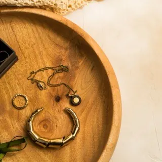 Nhẫn, dây chuyền và vòng tay vàng đặt trên khay gỗ tròn