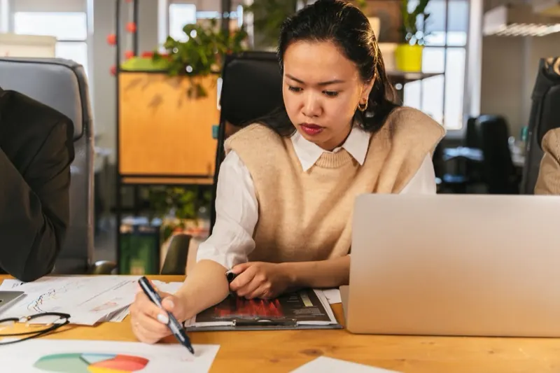 Chuyên viên xem báo cáo thị trường trên laptop tại văn phòng