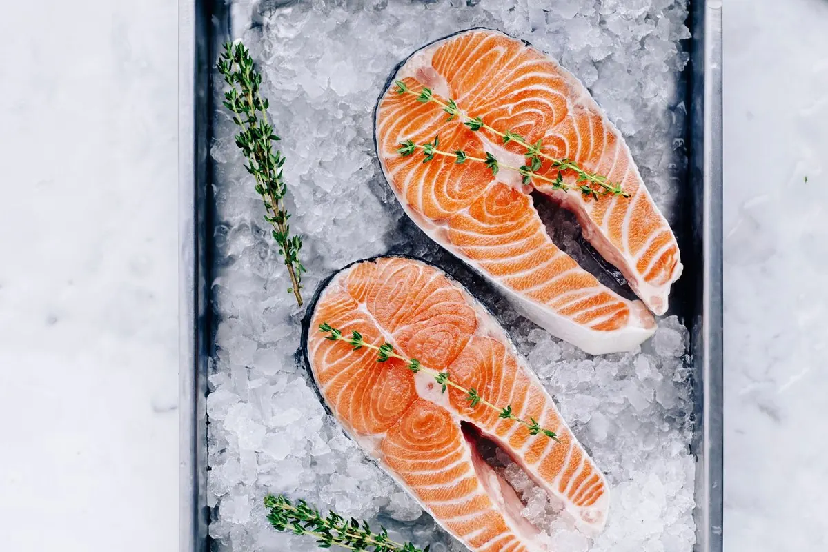 Two fresh salmon steaks on a tray of ice