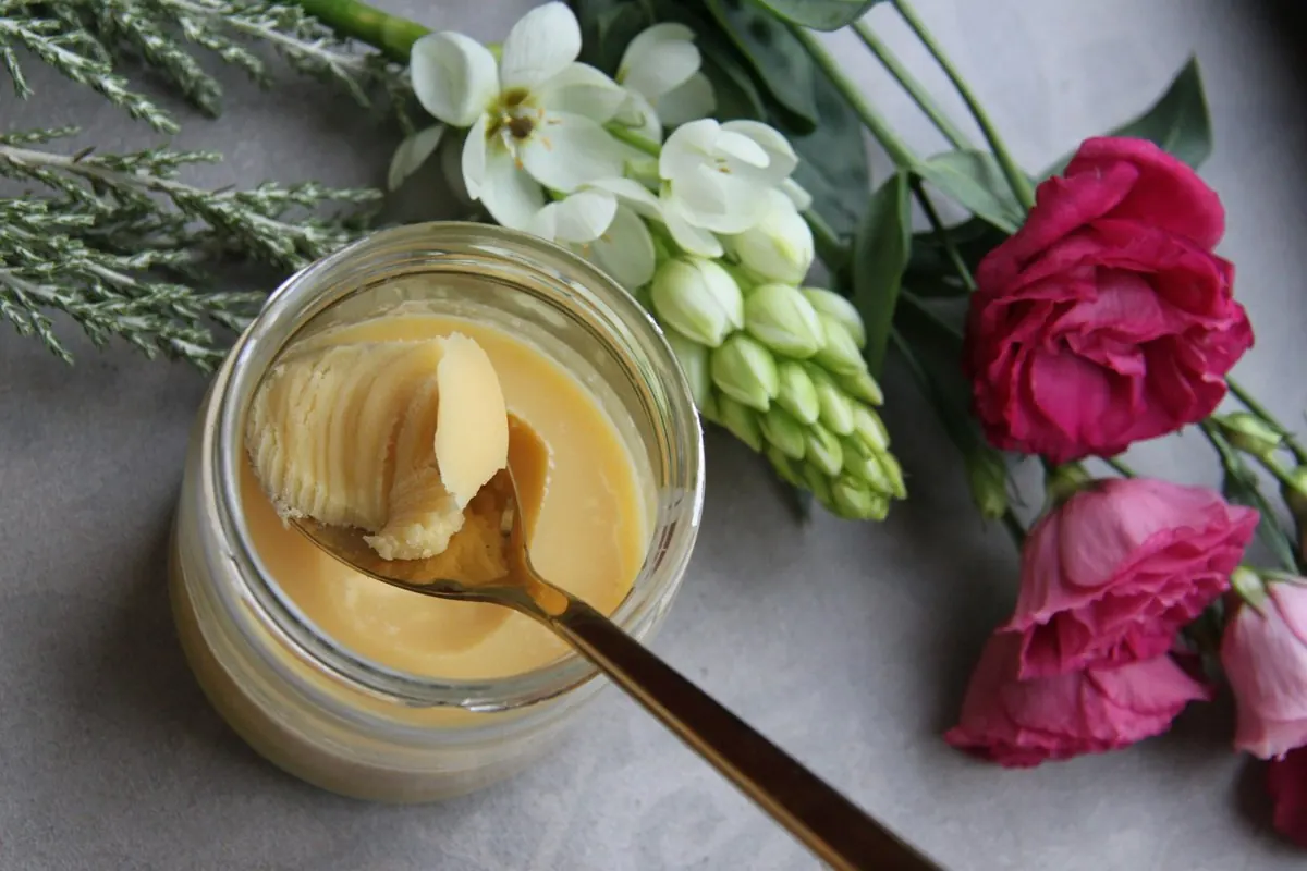 Hũ thủy tinh đựng bơ ghee vàng, muỗng múc trên mặt