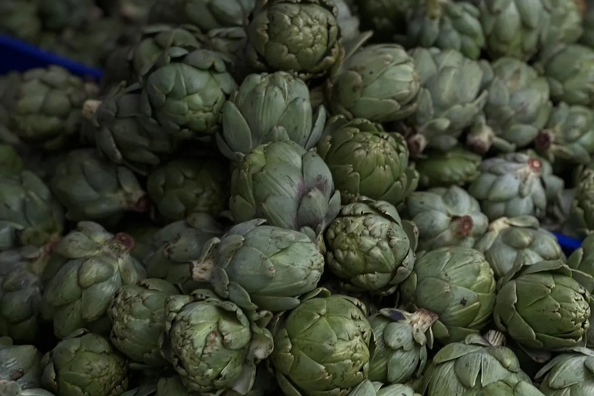 Fresh artichokes piled at a market stall