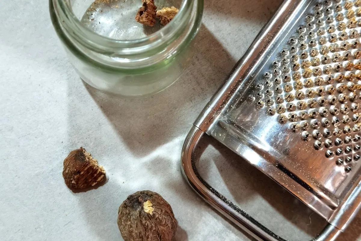 Hạt nhục đậu khấu, lọ thủy tinh và dụng cụ bào trên mặt bếp