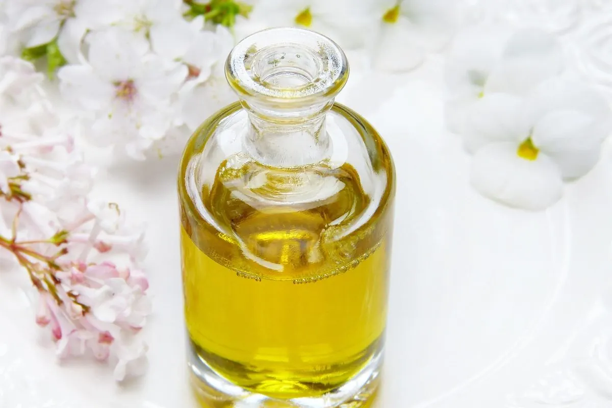 Chai thủy tinh đựng dầu vàng cạnh hoa trắng