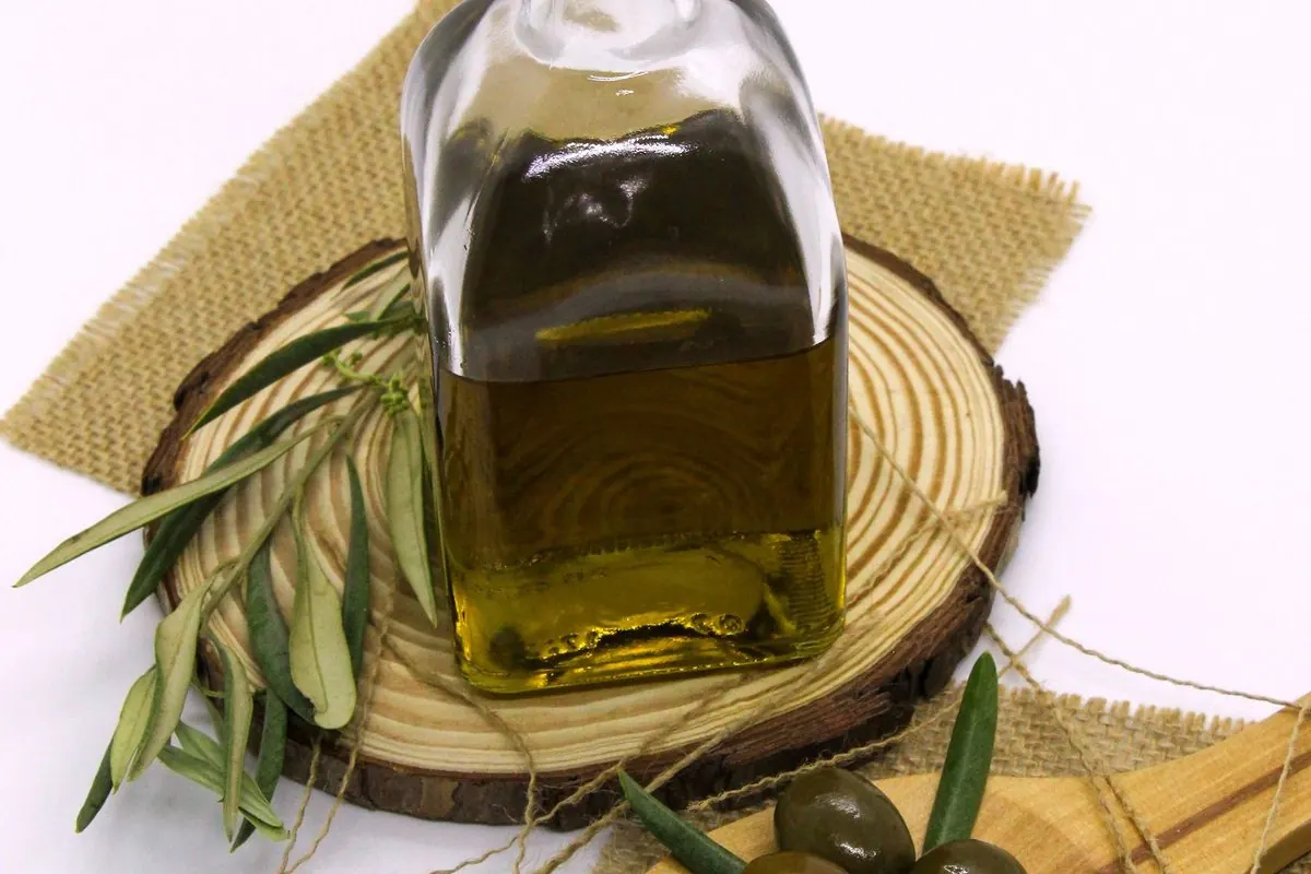 Chai thủy tinh dầu ô liu có nút bần cạnh quả ô liu