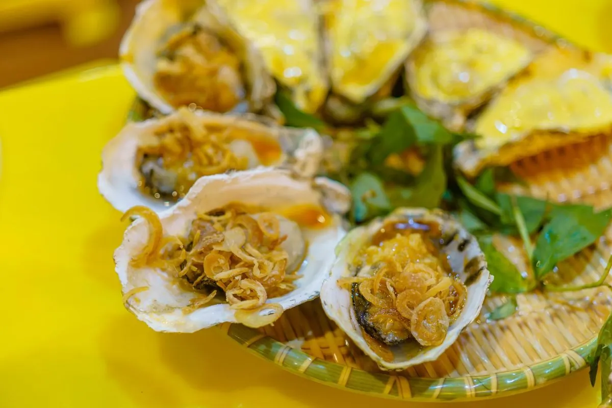 Grilled oysters topped with fried shallots on a bamboo tray