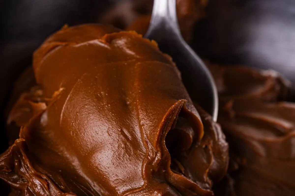 Smooth brown chocolate paste in a metal bowl with a spoon