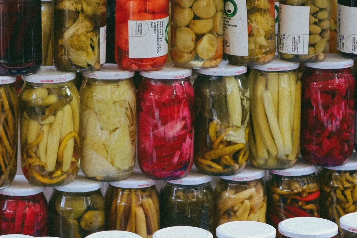 Stacked jars of assorted pickled vegetables at a market