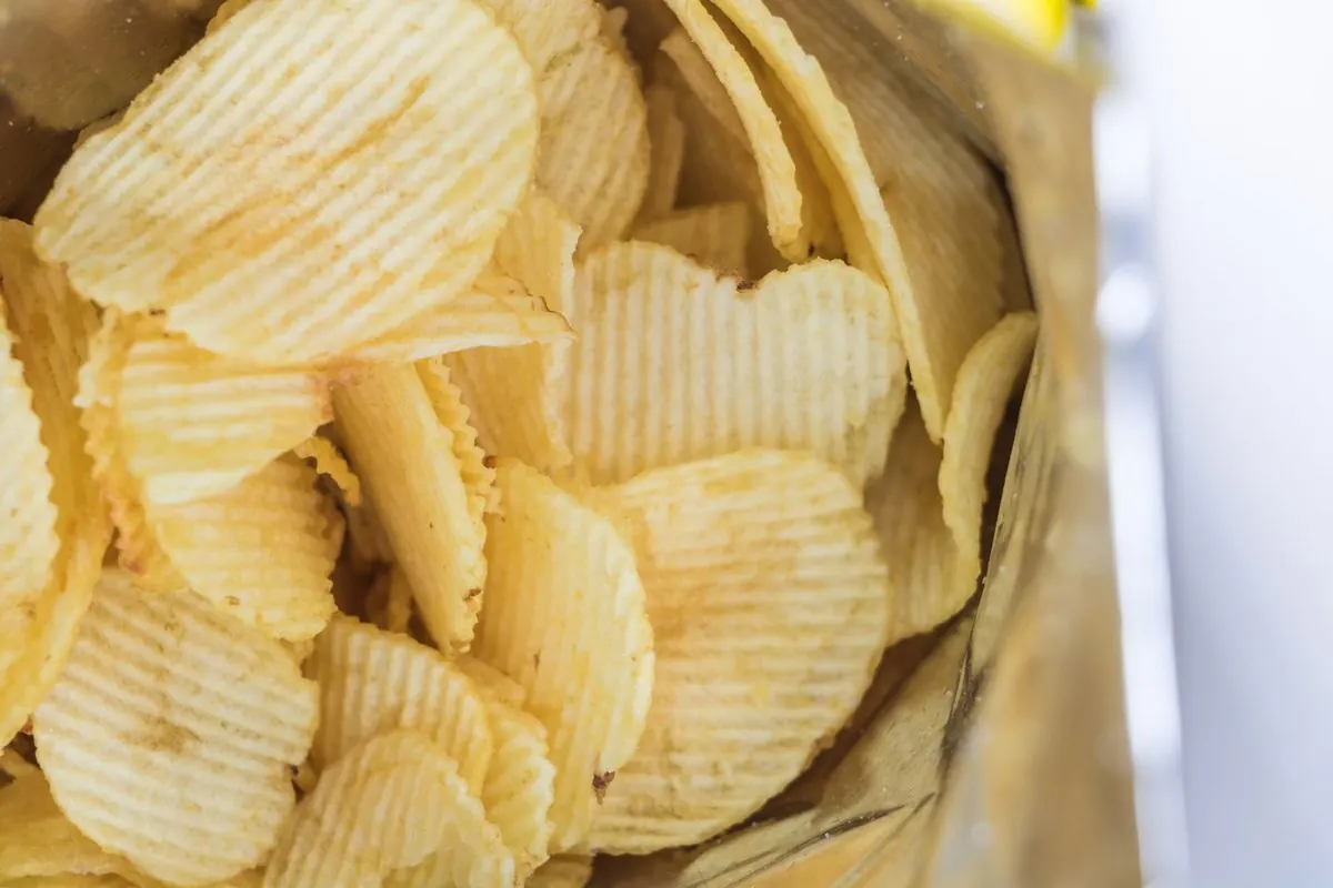 Ridged potato chips spilling from an open bag