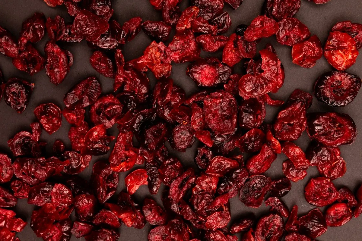Dried cranberries scattered on a dark surface