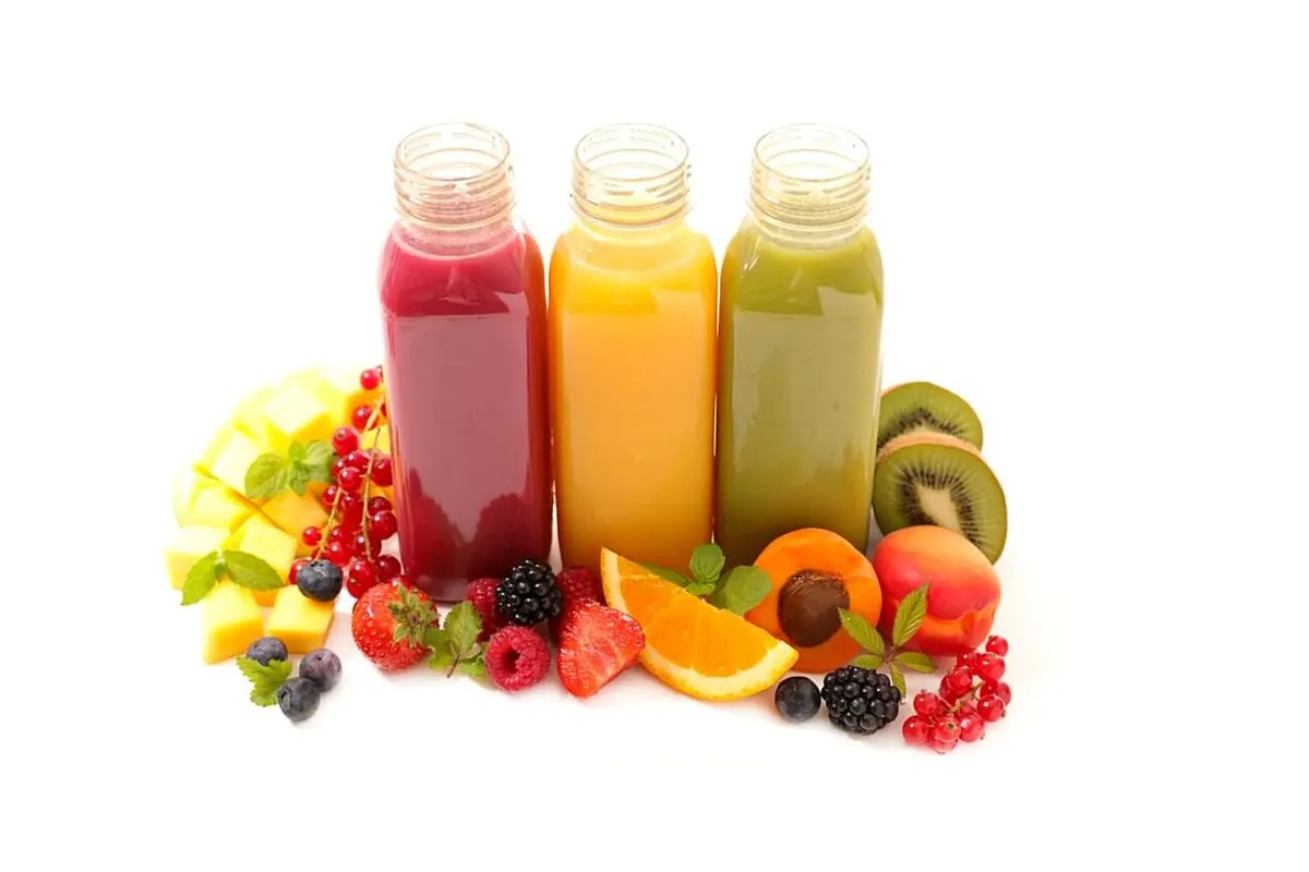 Ba chai nước ép đỏ, vàng, xanh bên trái cây tươi