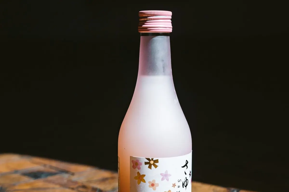 Chai sake thủy tinh mờ hồng đặt trên mặt gỗ