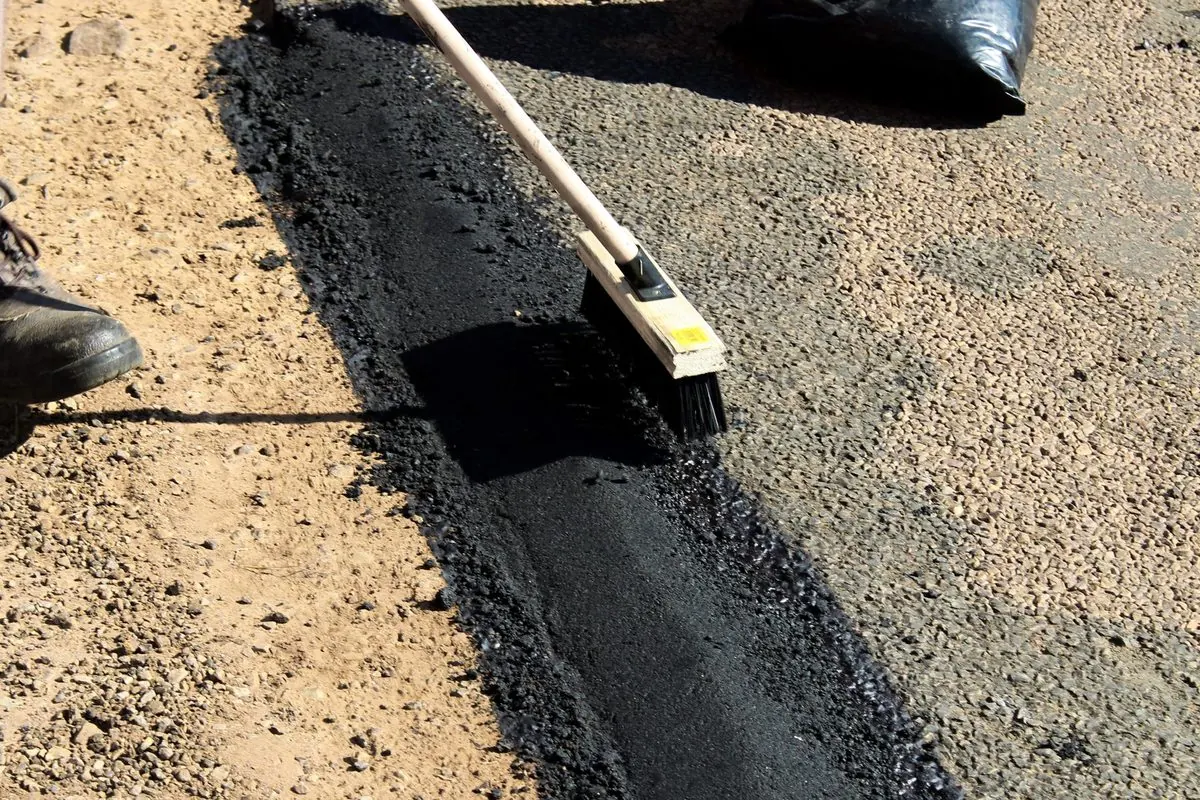 Lớp đá dăm trộn nhựa đường vừa rải, công nhân gạt bằng chổi
