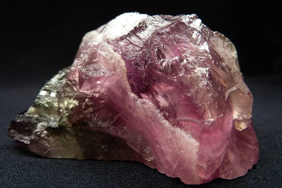Cục khoáng fluorite thô màu tím hồng trên nền tối