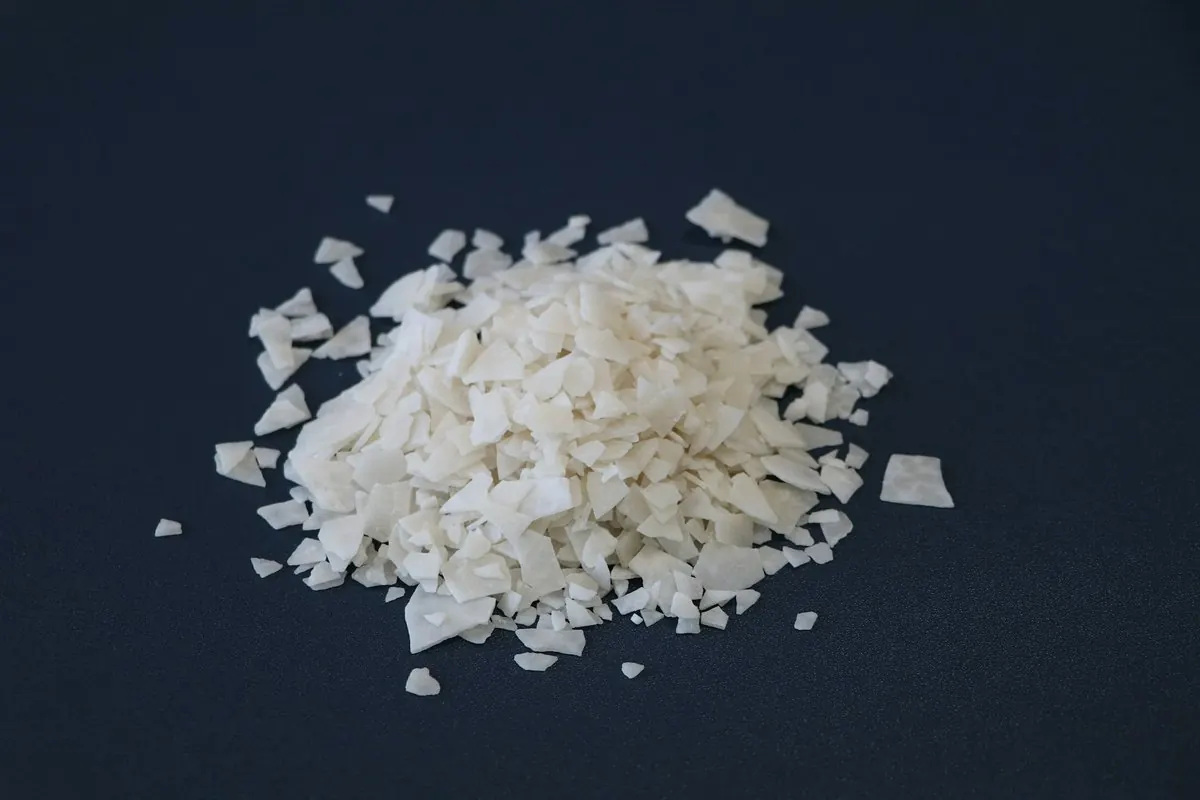 Pile of white magnesium chloride flakes on a dark blue background