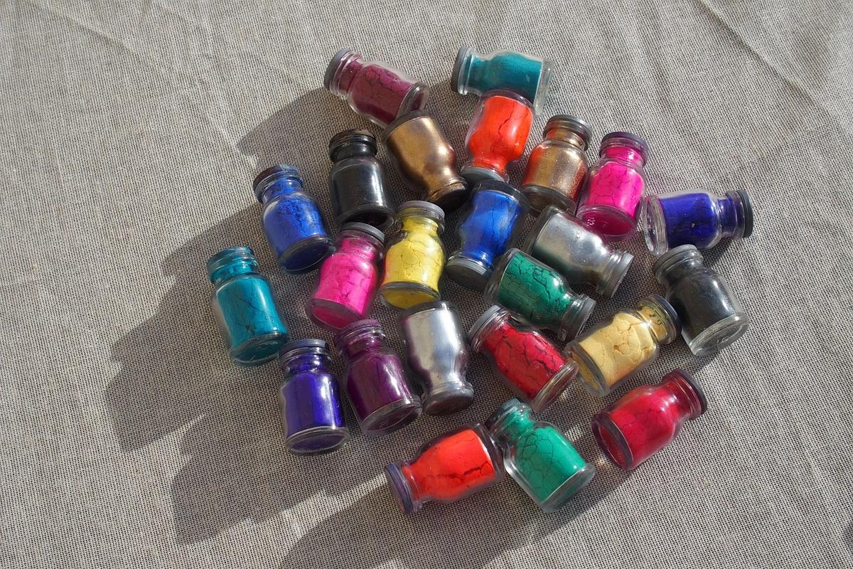 Nhiều lọ nhỏ đựng bột màu pigment đủ sắc trên nền vải