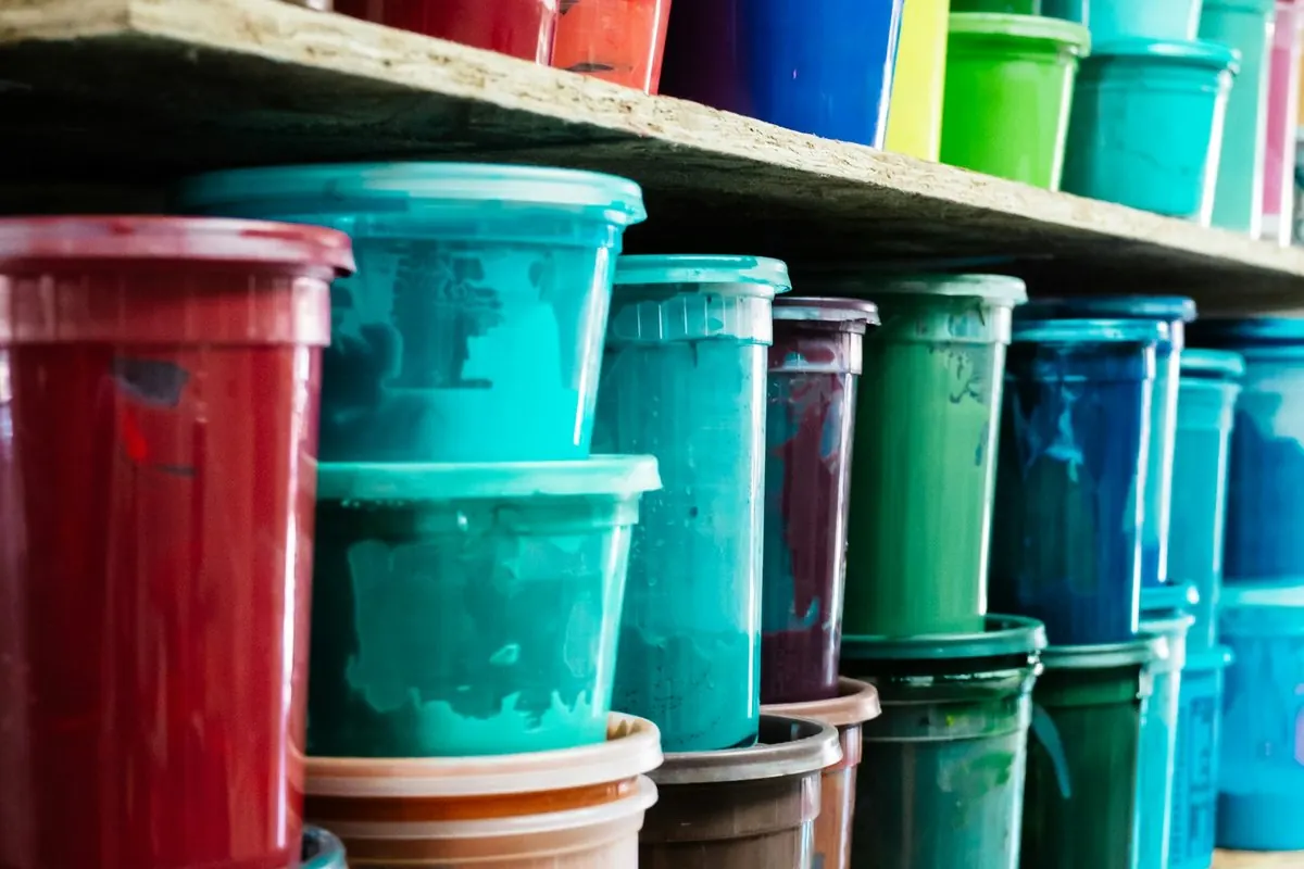 Tubs of coloured printing ink stacked on a print shop shelf