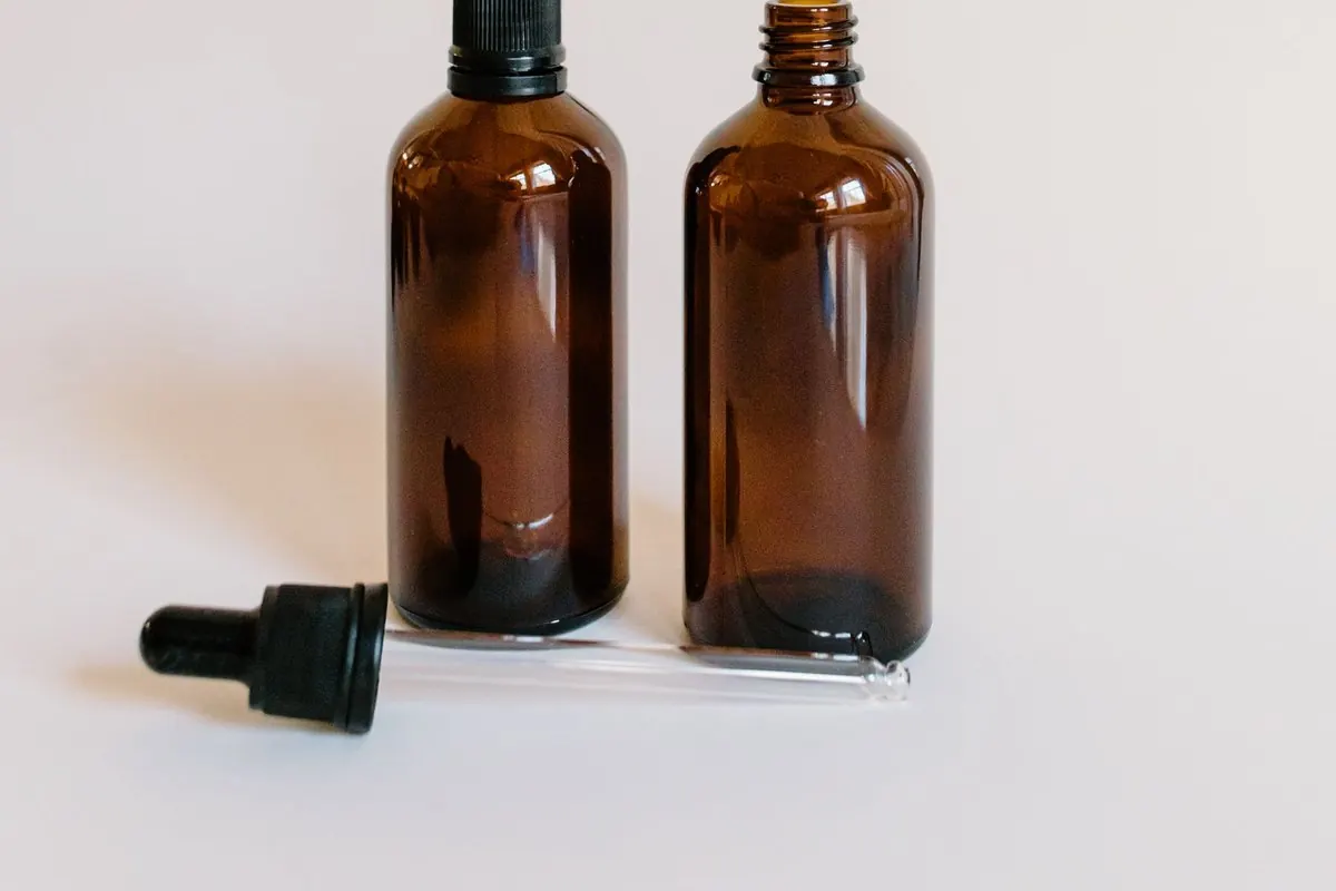 Two brown glass essential oil bottles and a dropper