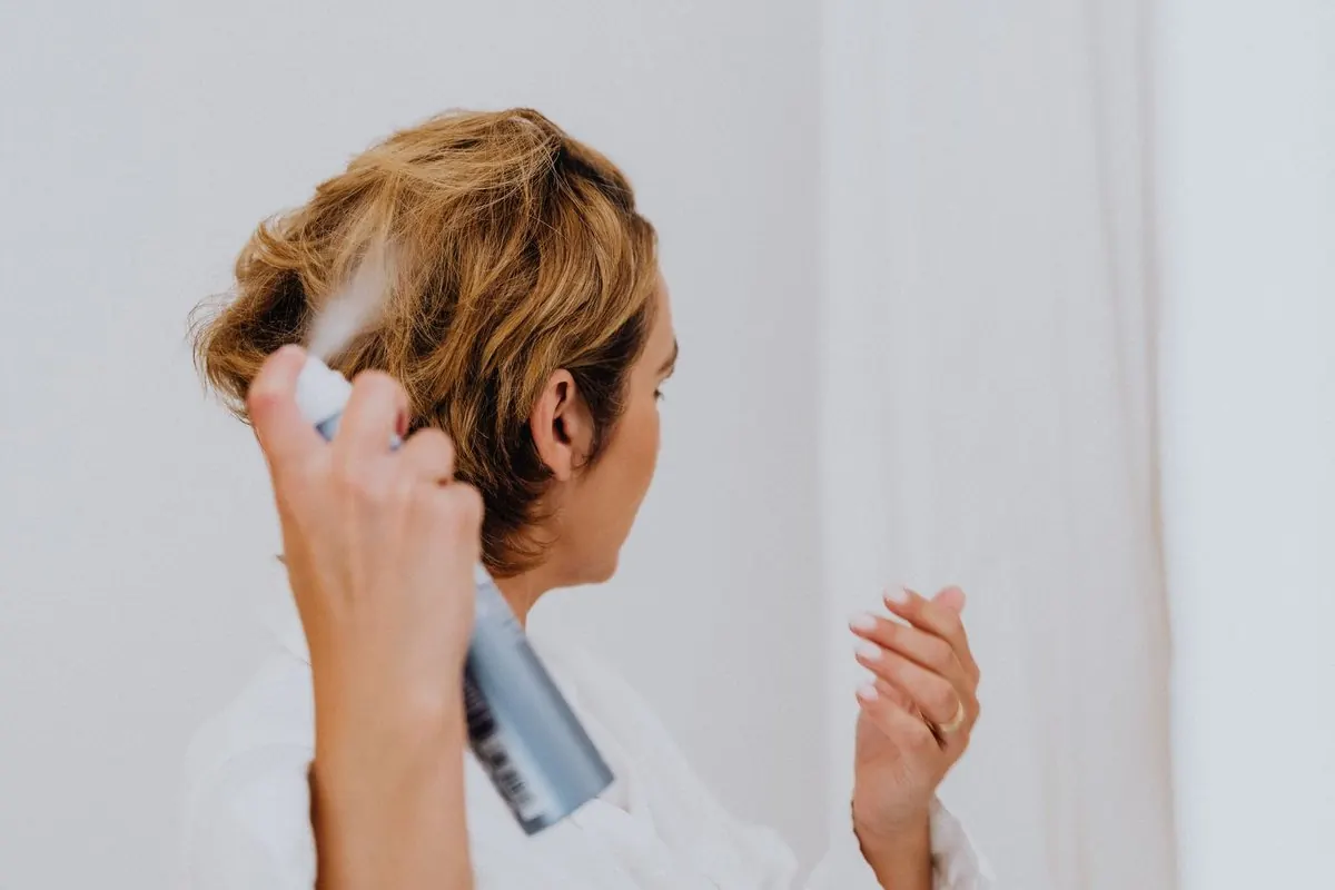Người phụ nữ cầm bình keo xịt tóc xịt lên mái tóc