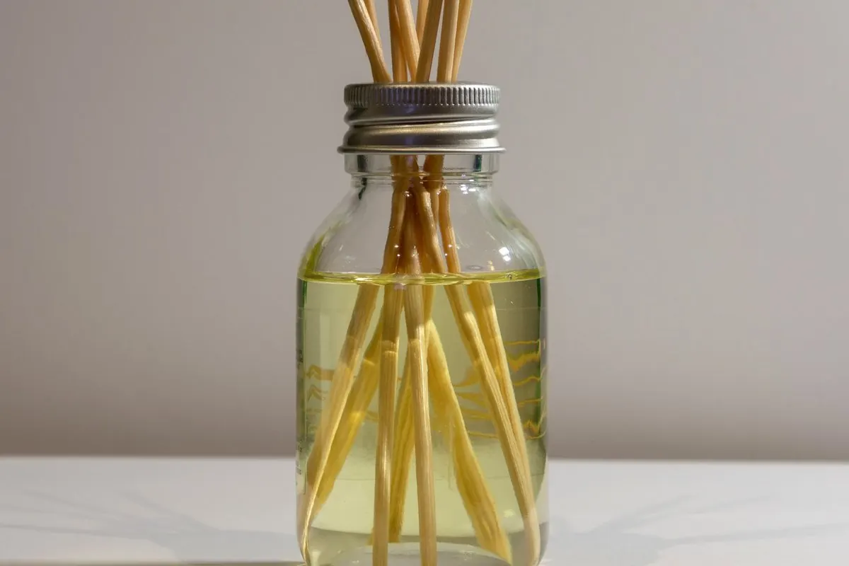 Glass jar of room fragrance oil with reed diffuser sticks