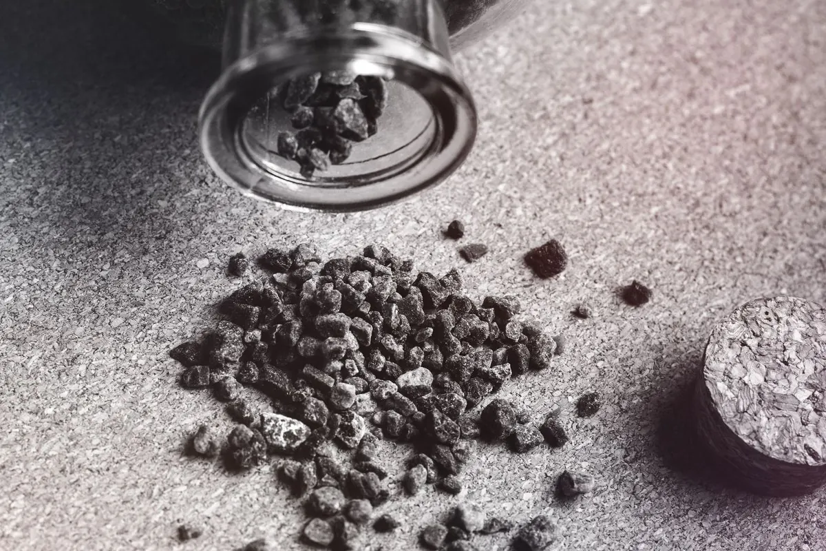 Activated carbon granules spilled from a glass jar onto a table