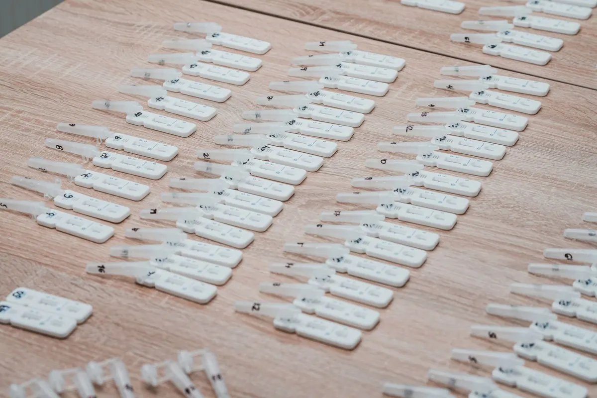Rows of rapid diagnostic test cassettes laid out on a wooden table