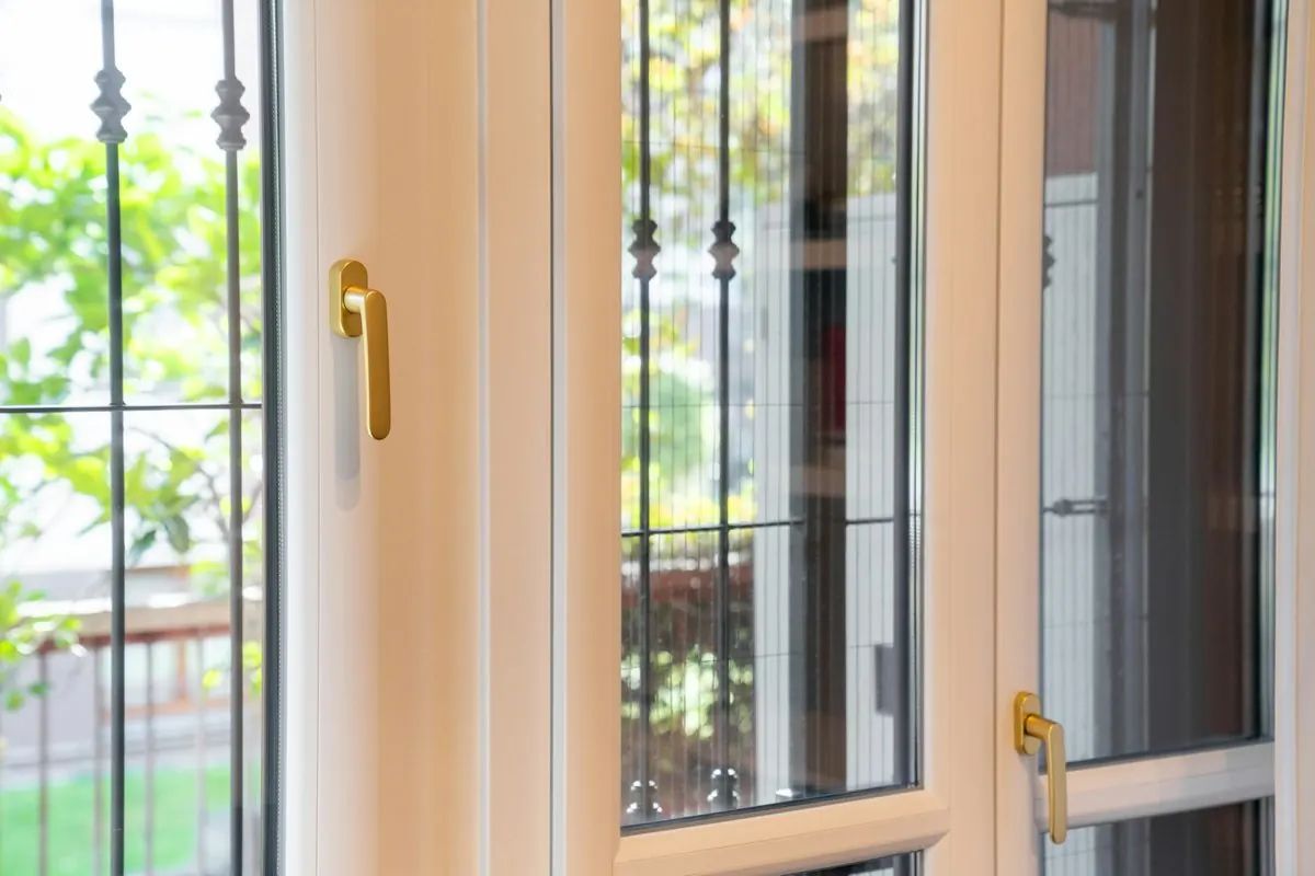 Cream plastic-framed window with gold handles opening onto a balcony