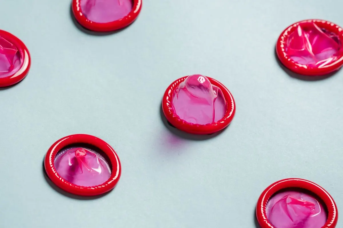 Pink condoms scattered across a light blue background