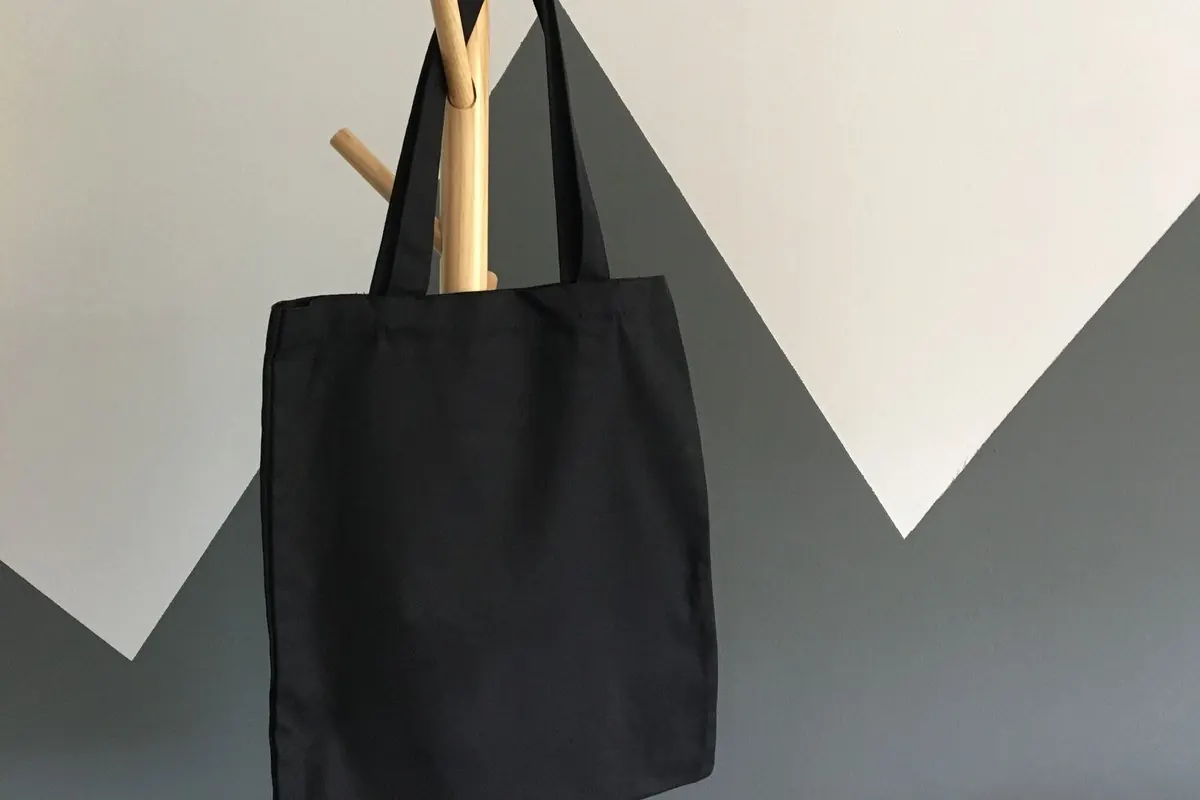 Túi tote vải canvas đen treo trên giá gỗ