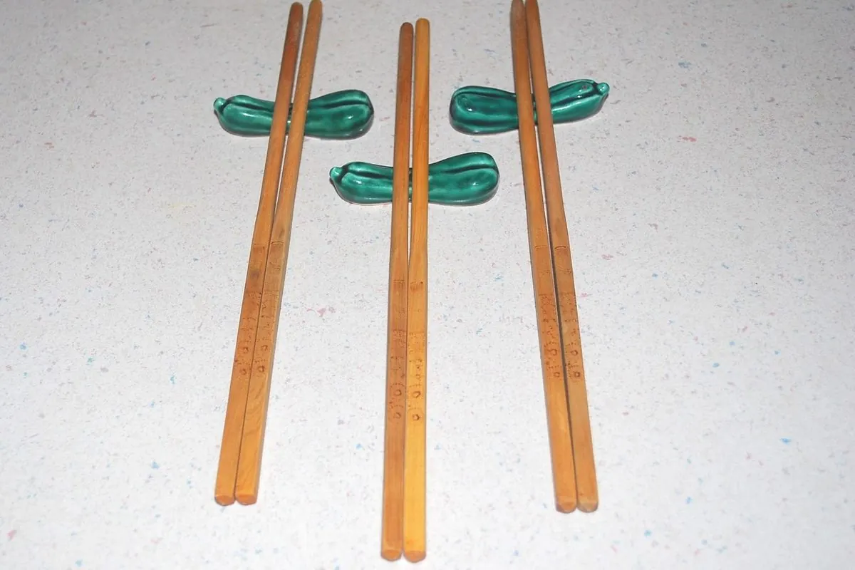 Three pairs of wooden chopsticks beside green chopstick rests
