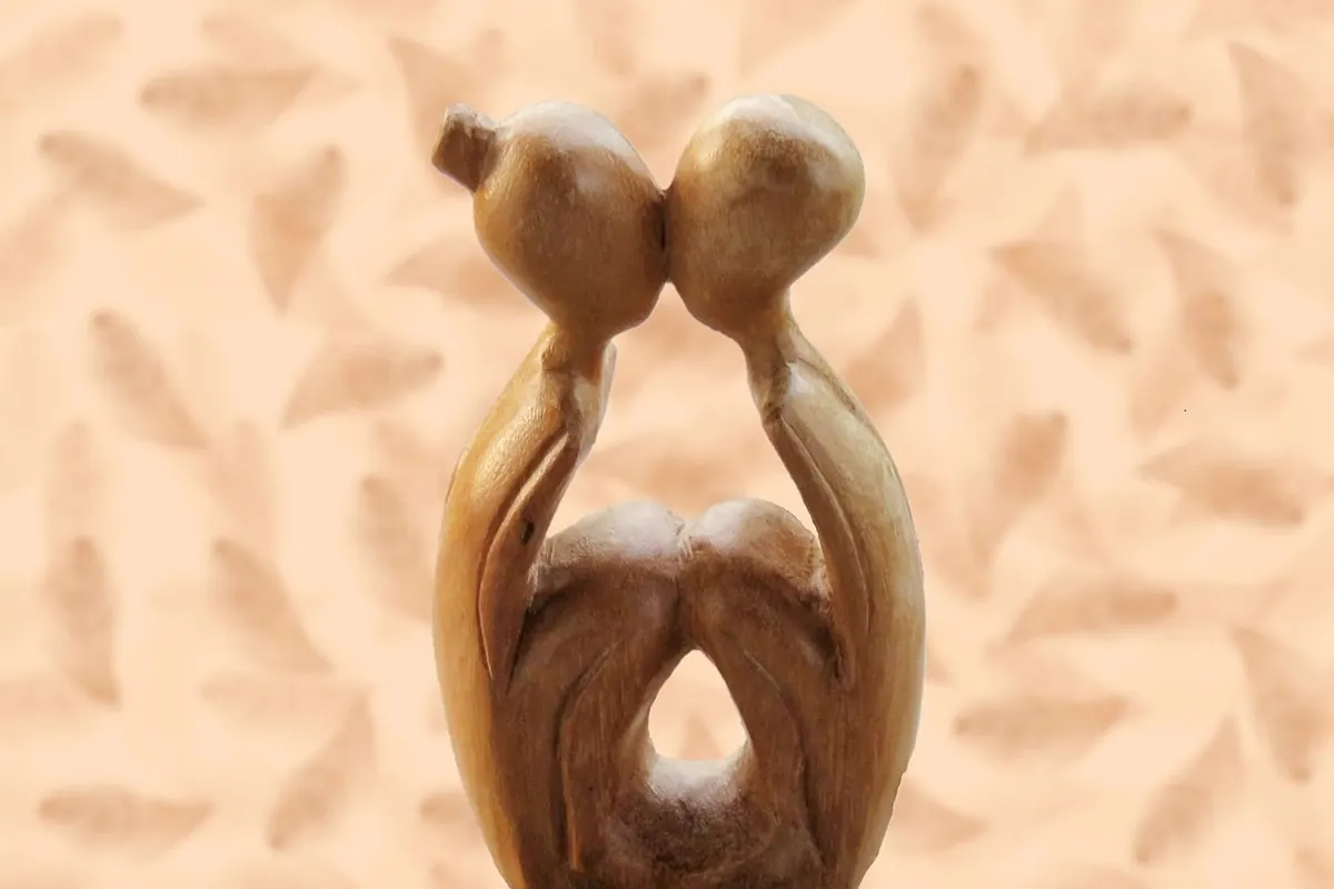 Carved wooden statue of two figures leaning close together