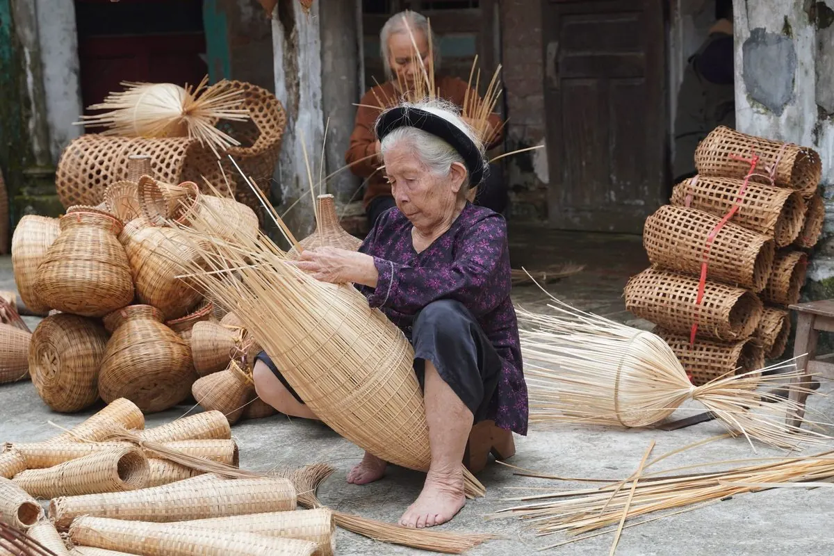 Nghệ nhân đan sản phẩm tre giữa các bó tre đan