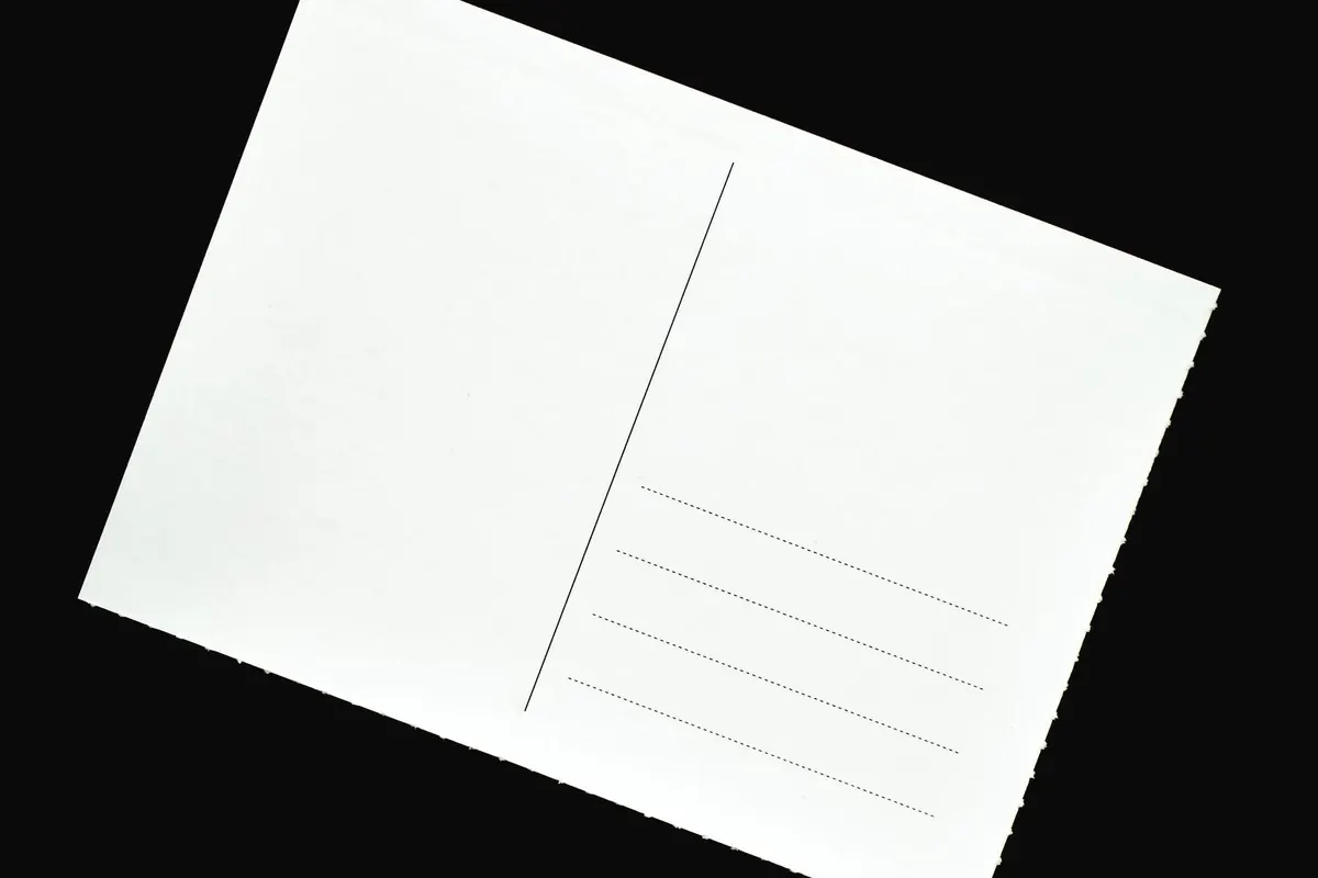 A blank white postcard lying on a black surface