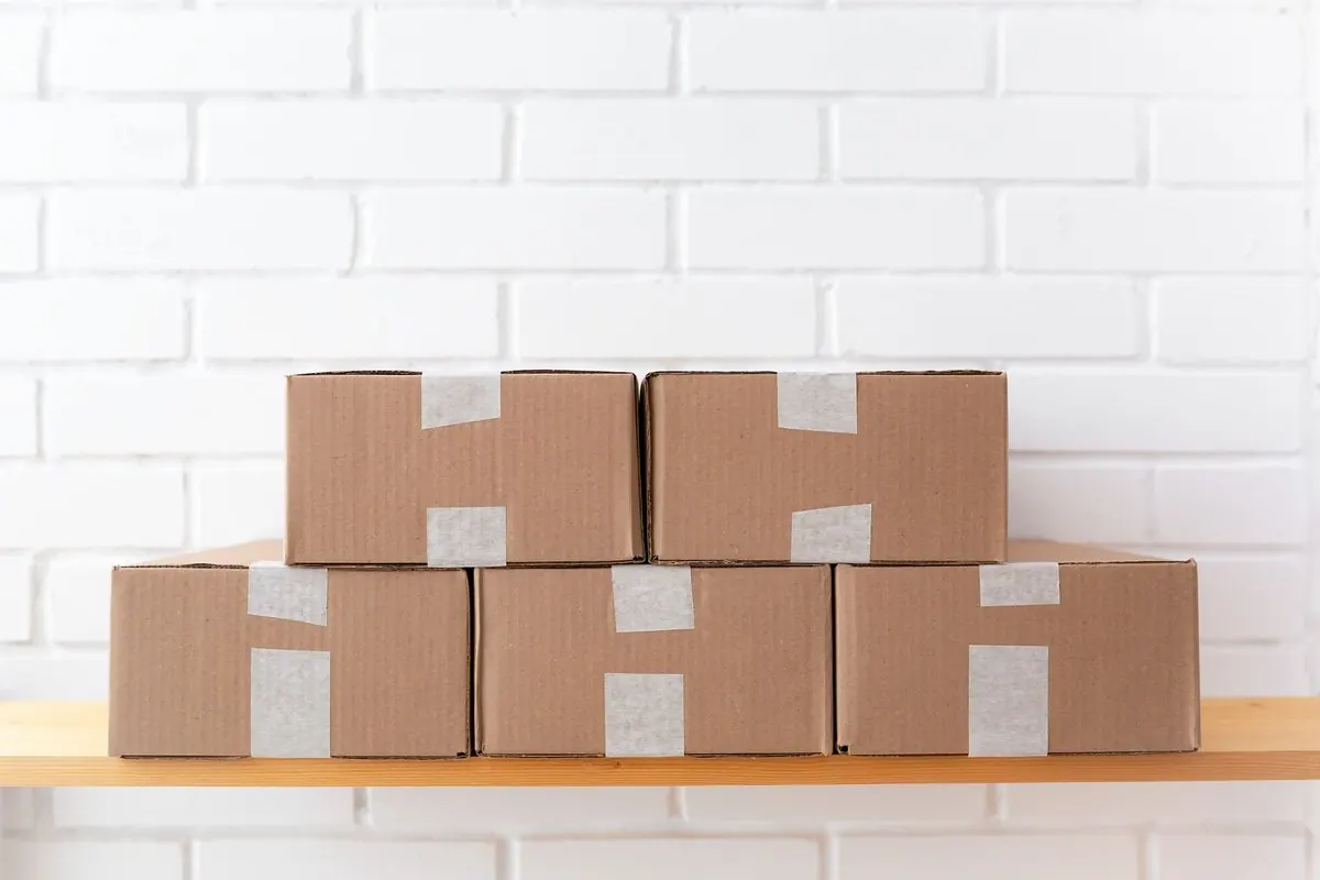 Năm thùng carton sóng dán băng keo xếp trên kệ gỗ