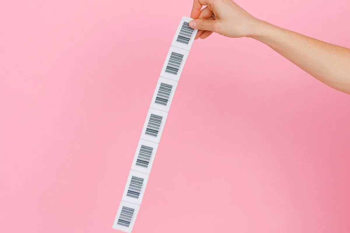 Tay cầm dải nhãn giấy đã in mã vạch trên nền hồng