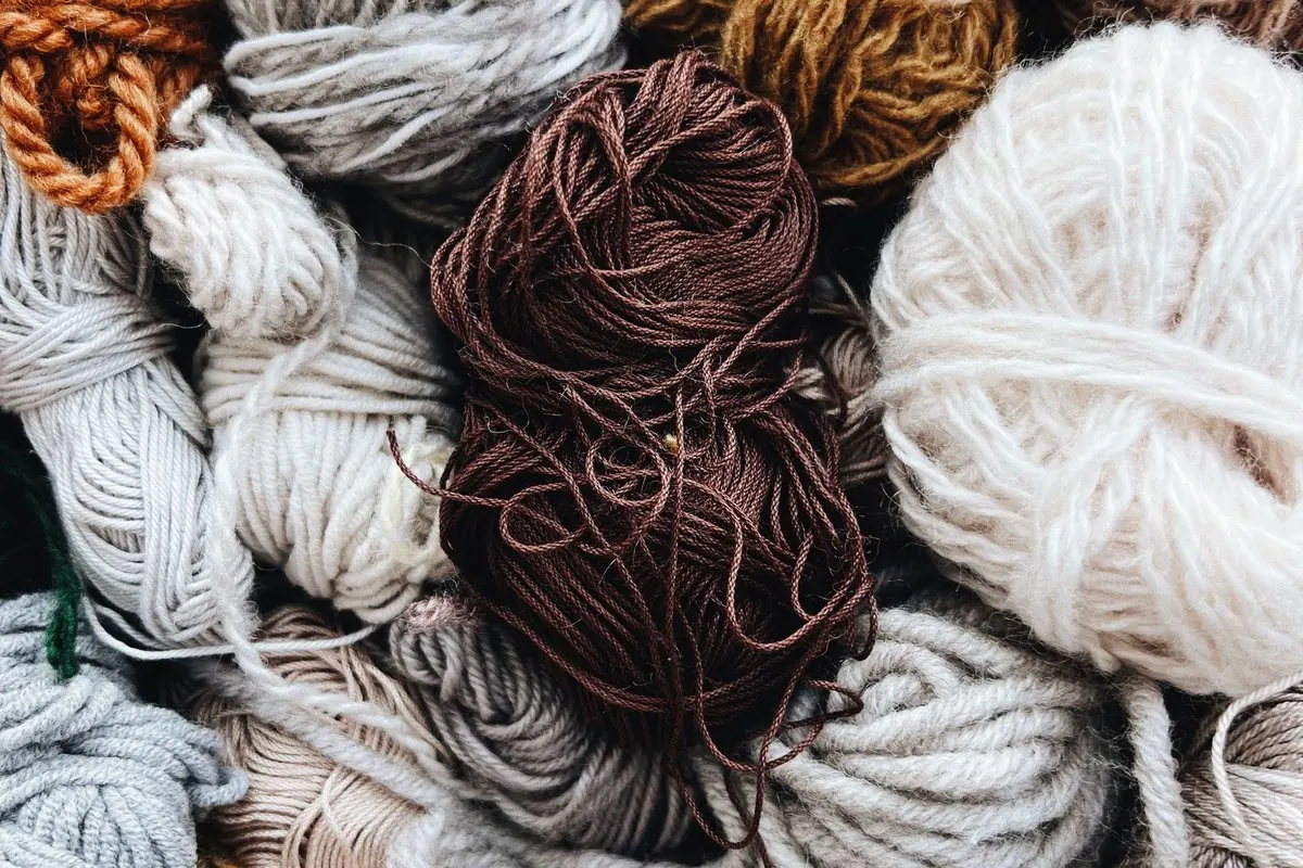 Hanks and balls of natural coloured wool yarn piled together