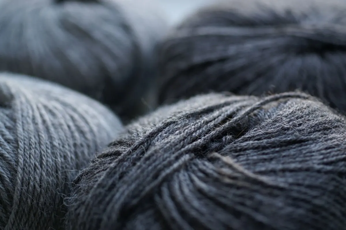 Dark grey wool yarn skeins lying side by side, close-up