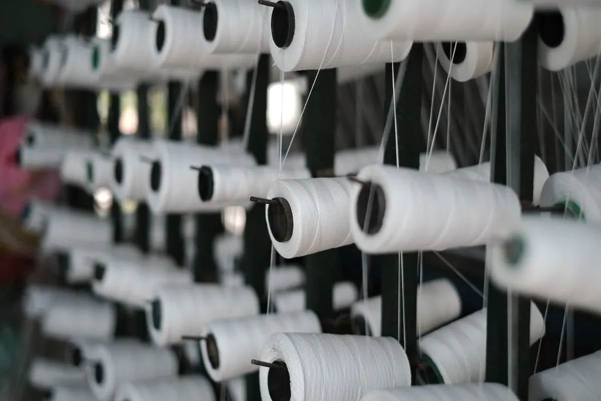 White sewing thread cones on a winding rack in a workshop