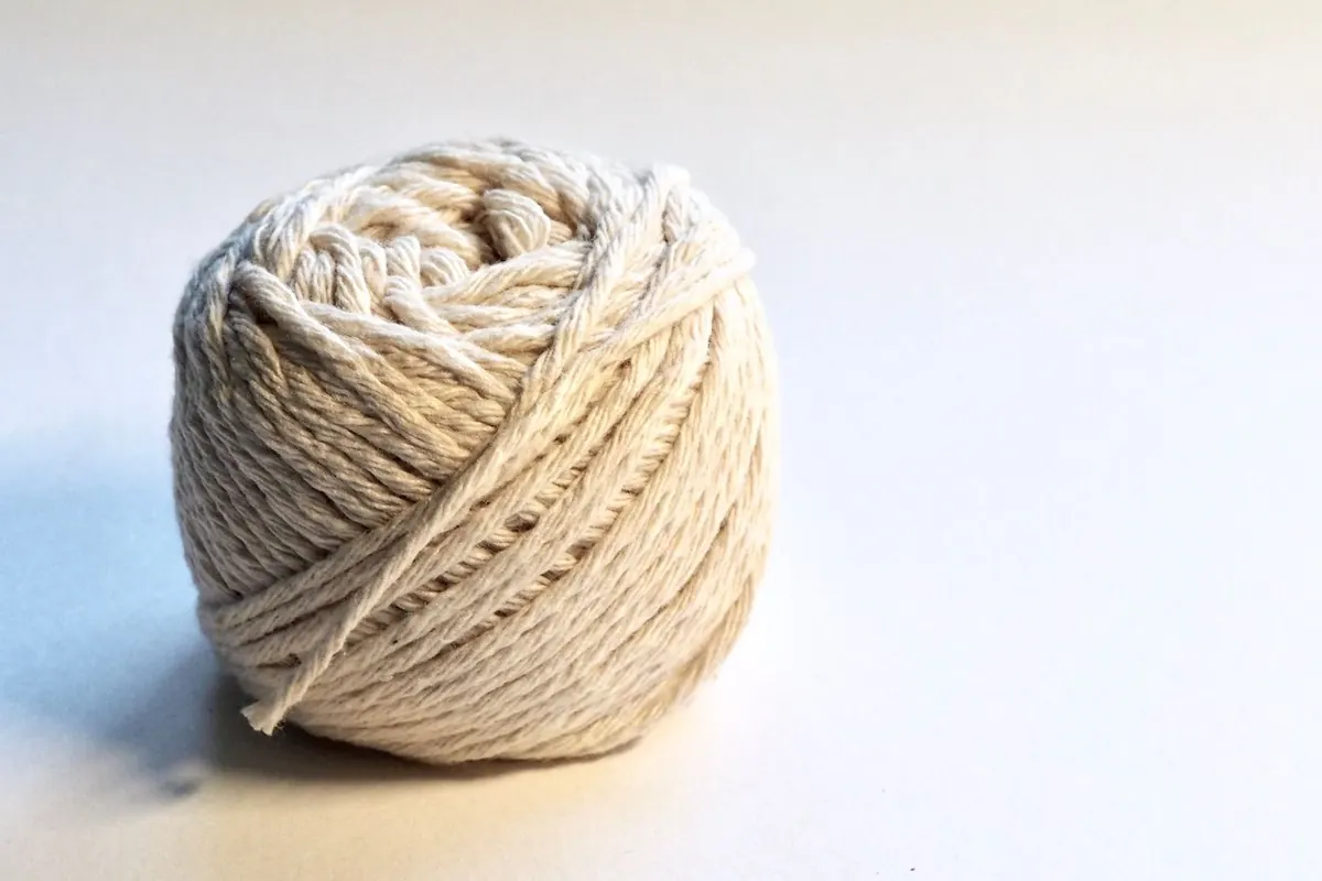 Ball of off-white cotton yarn on a white background