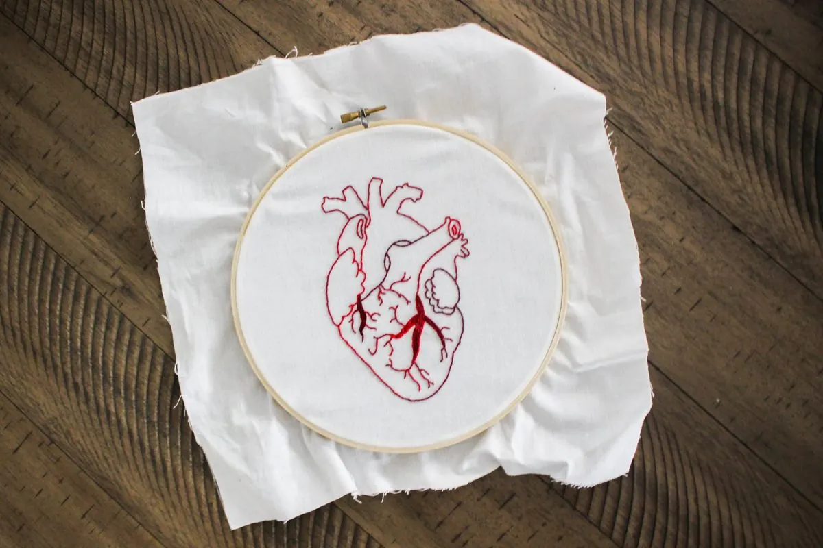 Hand-embroidered heart in an embroidery hoop on white fabric