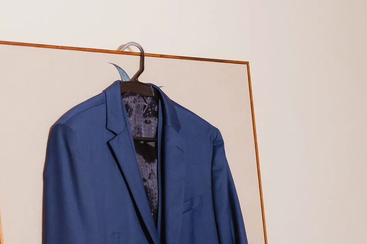 Áo blazer xanh cobalt treo trên móc cạnh khung tranh