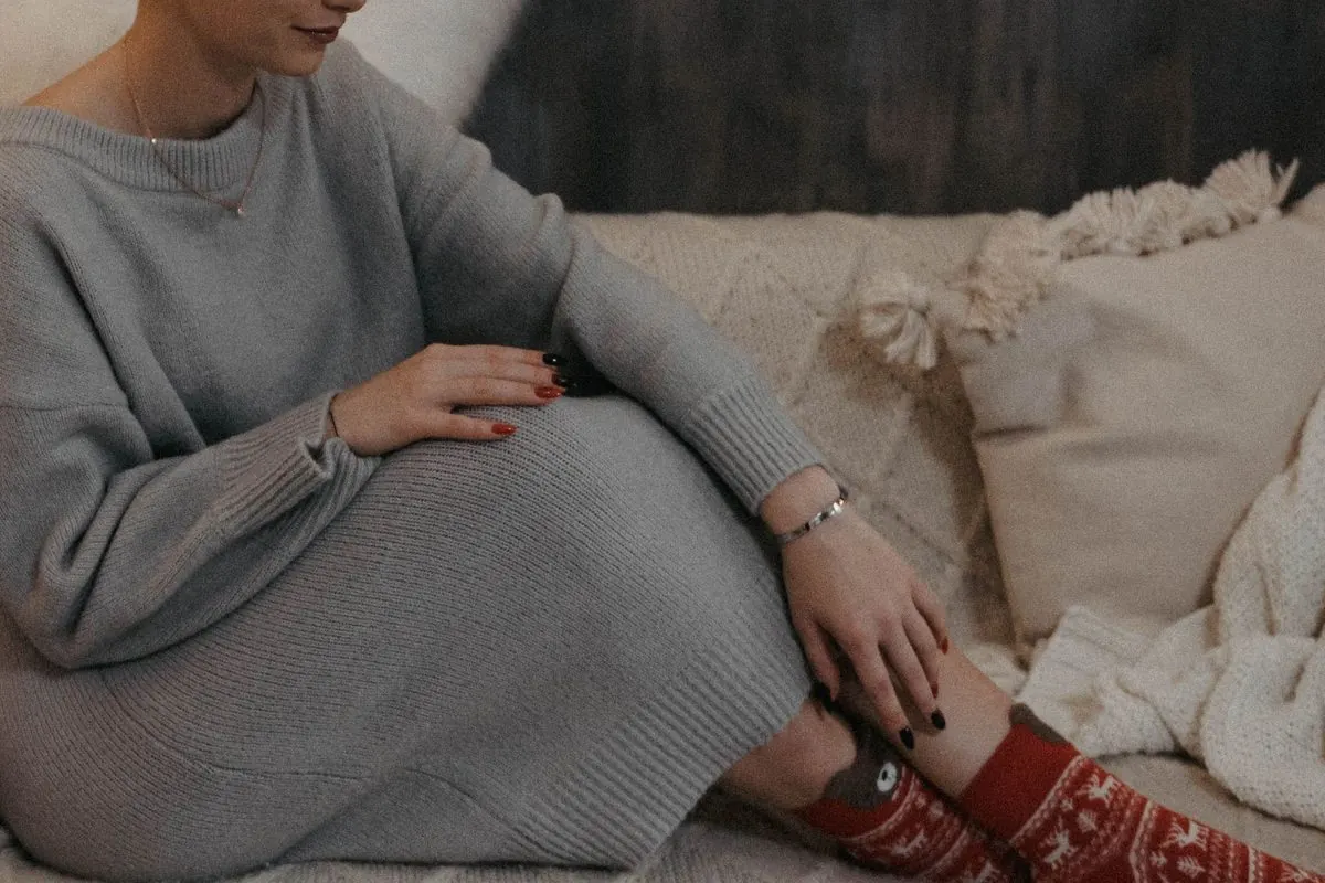 Váy len dệt kim xám dáng rộng, người ngồi trên ghế sofa