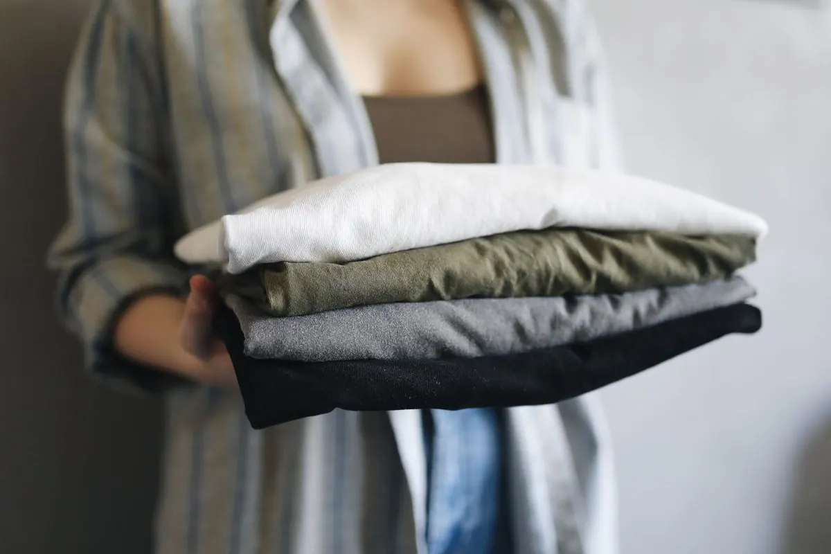 Chồng áo thun gấp gọn nhiều màu trên tay người