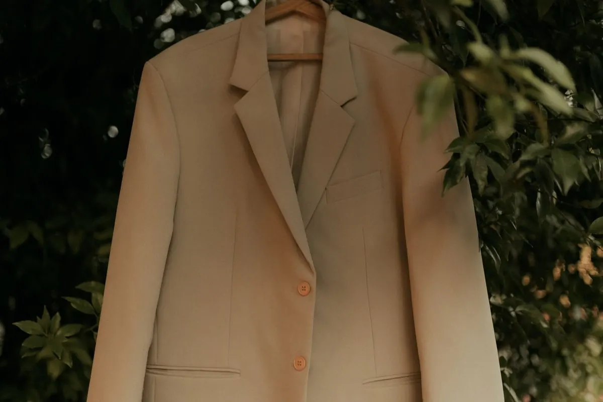 Áo blazer nữ màu be treo ngoài trời giữa tán cây
