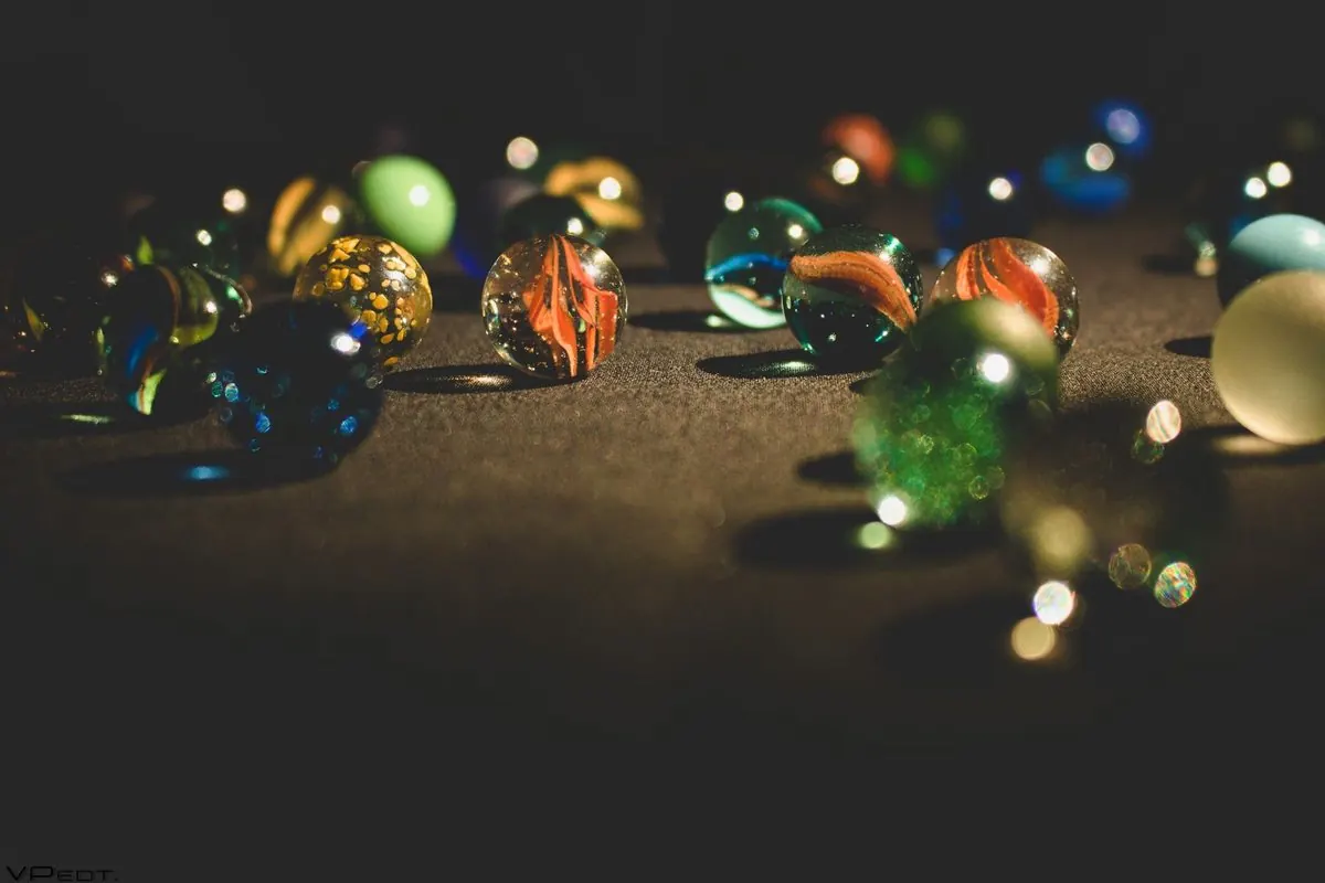Many multicoloured glass marbles on a dark surface