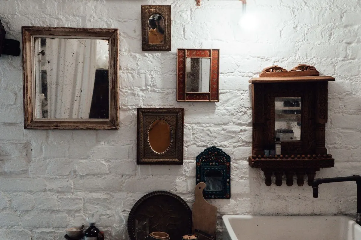 Framed mirrors hanging on a brick wall