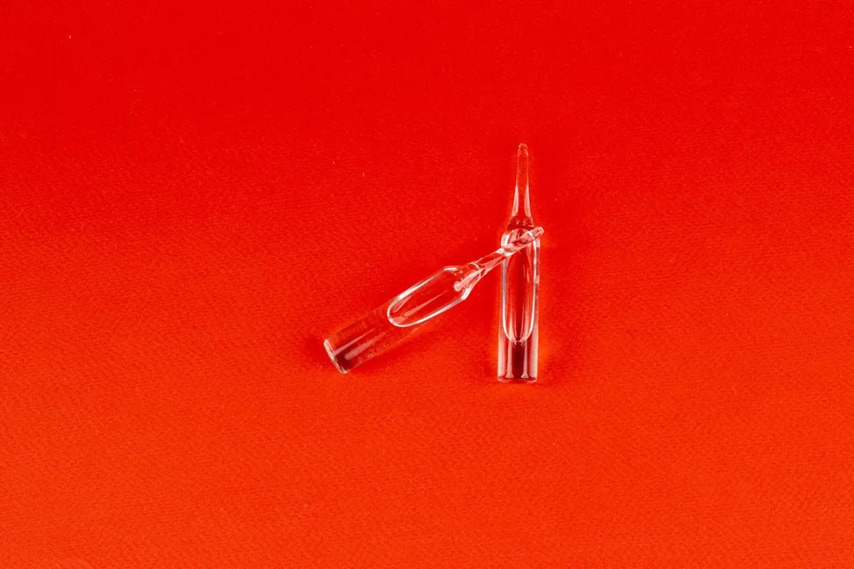 Hai ống thủy tinh ampoule trong suốt đặt trên nền đỏ