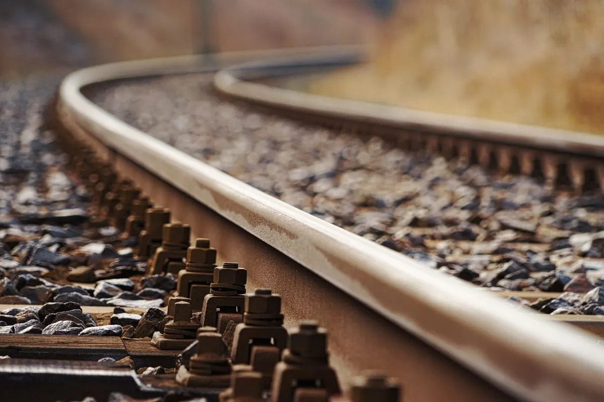 Curved steel railway track with fastening bolts on ballast