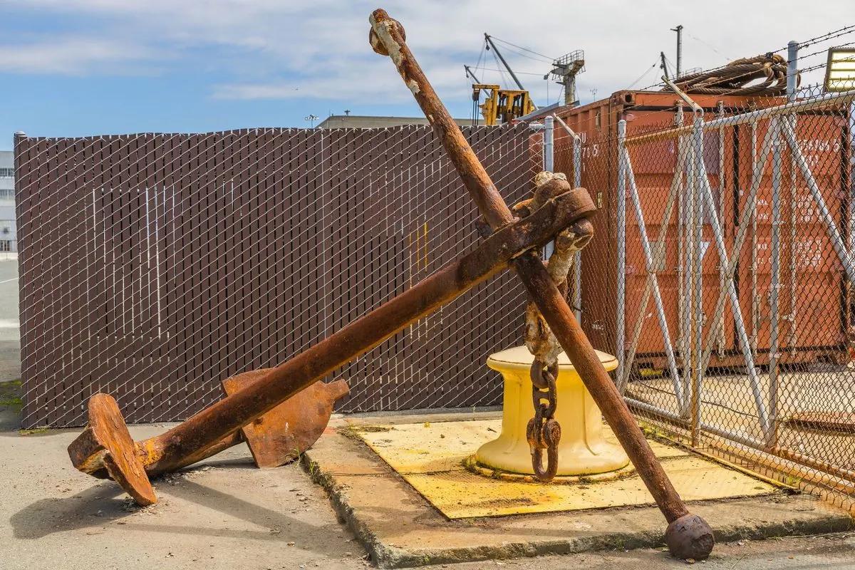 Large rusty steel ship anchor lying in a port