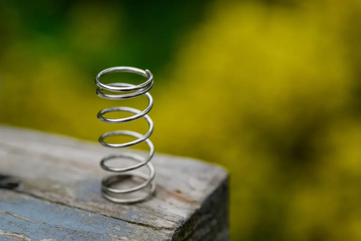 Steel coil spring standing on a wooden surface